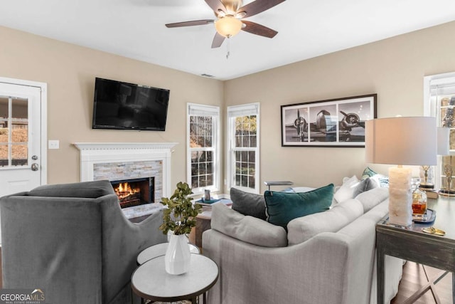 living area with a fireplace, a ceiling fan, and visible vents