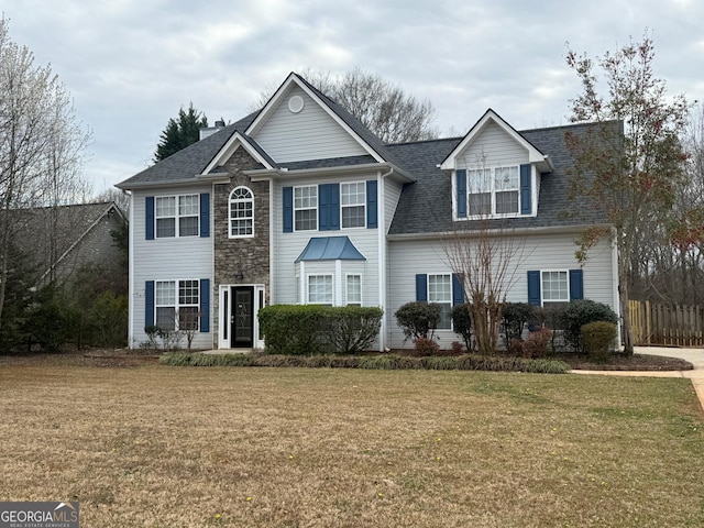 view of front of home with stone siding, a front lawn, and fence