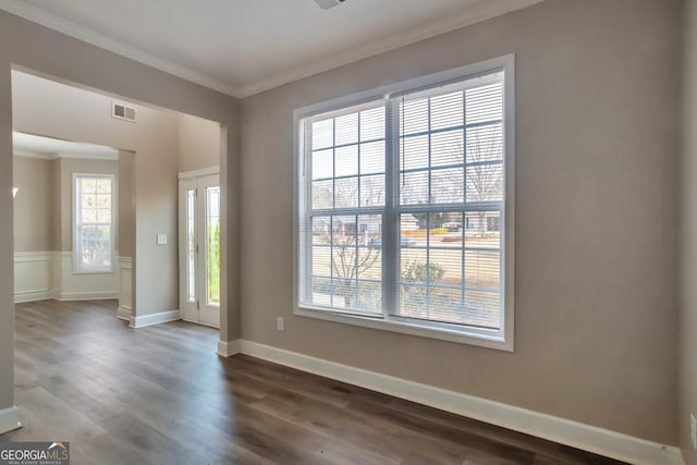 unfurnished room featuring visible vents, baseboards, ornamental molding, and dark wood finished floors