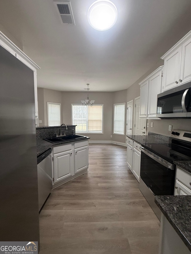 kitchen featuring visible vents, appliances with stainless steel finishes, white cabinetry, and a sink