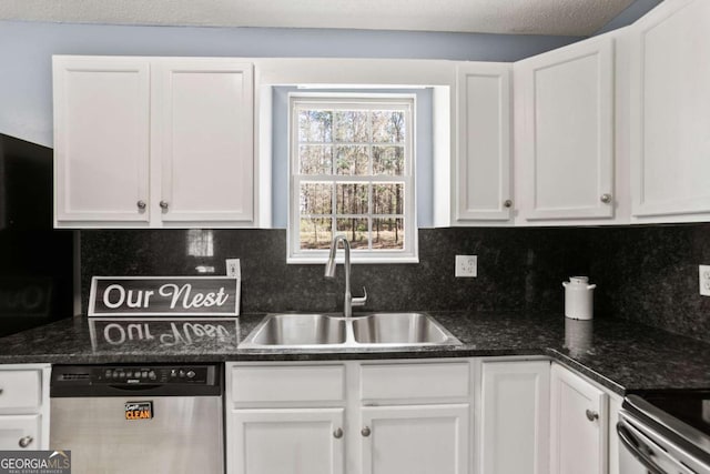 kitchen featuring dark stone countertops, a sink, white cabinets, appliances with stainless steel finishes, and backsplash