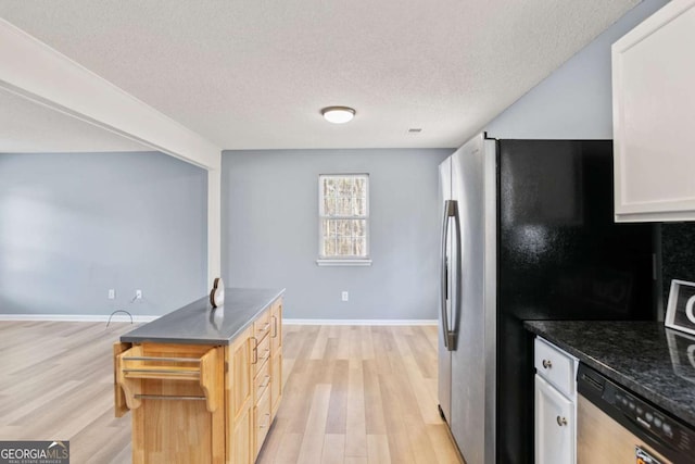 kitchen with baseboards, stainless steel appliances, white cabinets, light wood-style floors, and a textured ceiling