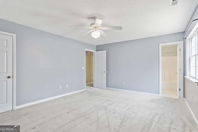 unfurnished bedroom with visible vents, baseboards, carpet floors, a textured ceiling, and ensuite bath