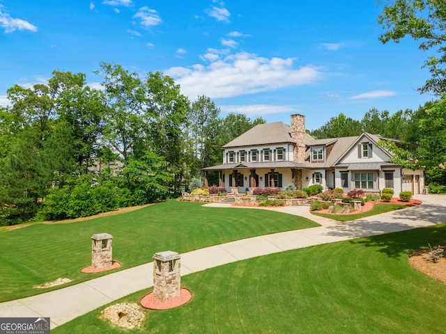 view of front of property featuring driveway, a front lawn, covered porch, a balcony, and a chimney