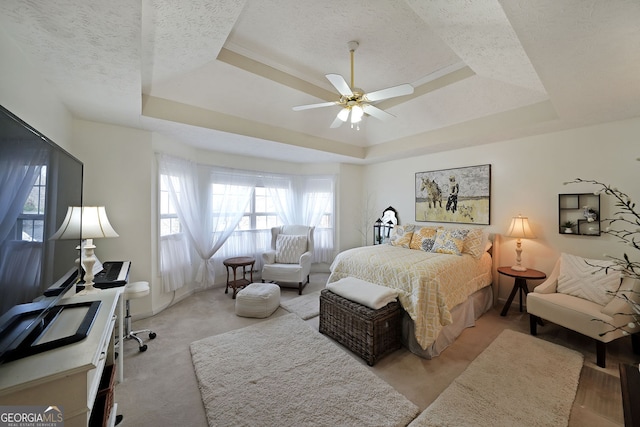 bedroom with ceiling fan, a tray ceiling, and a textured ceiling