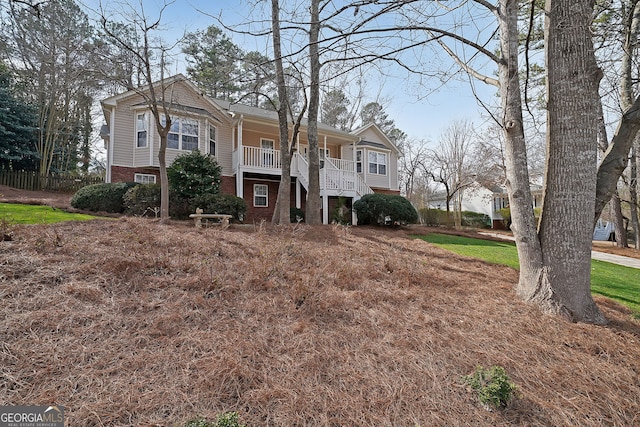 view of front of home with brick siding, a porch, and stairs