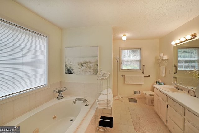 full bathroom featuring visible vents, toilet, vanity, a tub with jets, and a textured ceiling