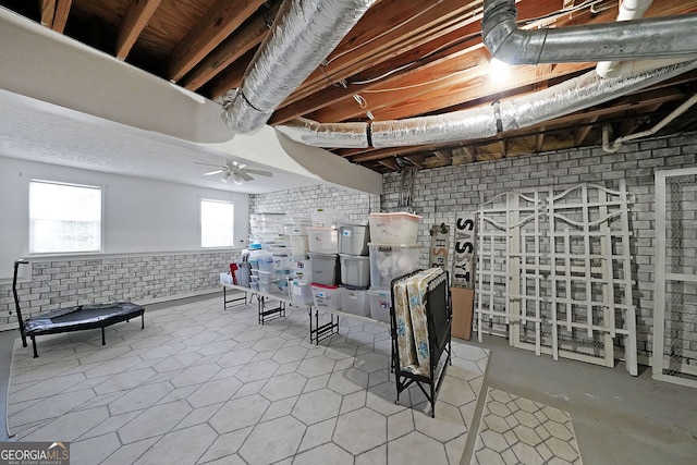 below grade area featuring a wainscoted wall, brick wall, and ceiling fan