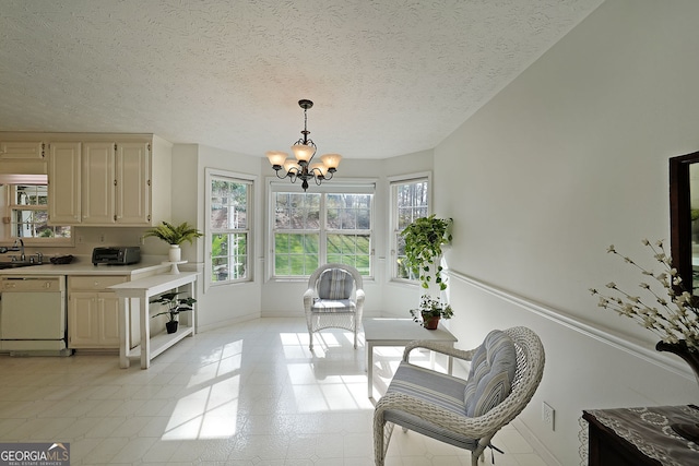 living area with an inviting chandelier, a toaster, baseboards, and a textured ceiling