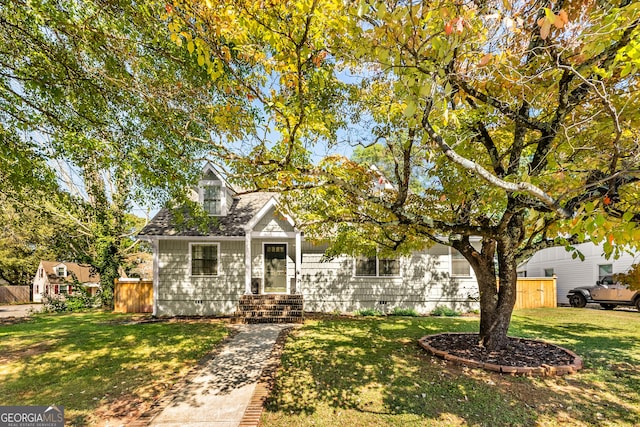 view of front facade with a front lawn, fence, roof with shingles, and crawl space