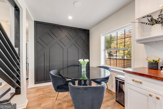 dining space with an accent wall, stairs, light wood-style floors, and recessed lighting