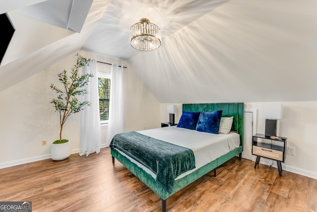 bedroom with vaulted ceiling, wood finished floors, and baseboards