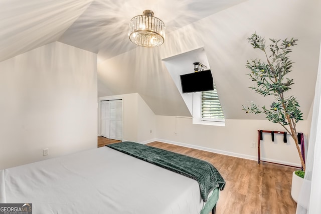 bedroom featuring a closet, lofted ceiling, baseboards, and wood finished floors