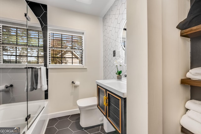 full bathroom featuring vanity, a tub to relax in, baseboards, tile patterned floors, and toilet