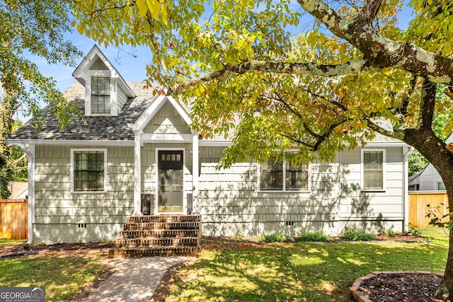 view of front of property featuring crawl space, a shingled roof, a front lawn, and fence