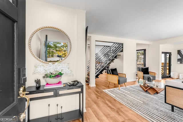 living area with stairs, baseboards, and light wood finished floors