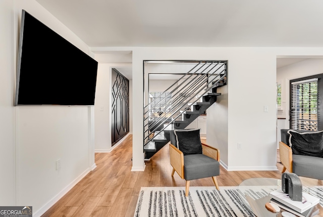 living room featuring stairway, baseboards, and light wood-style floors