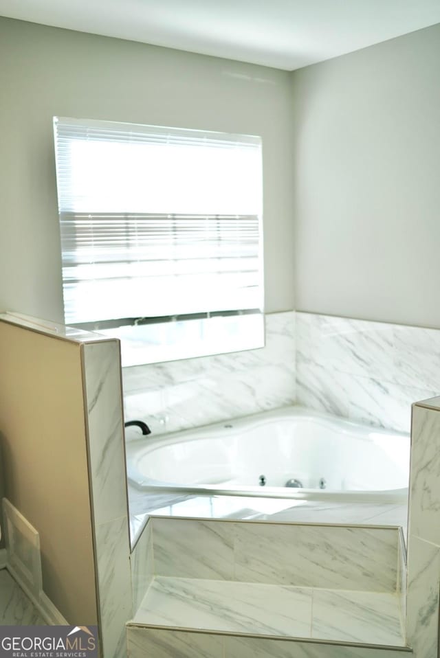 bathroom with a wealth of natural light and a tub with jets