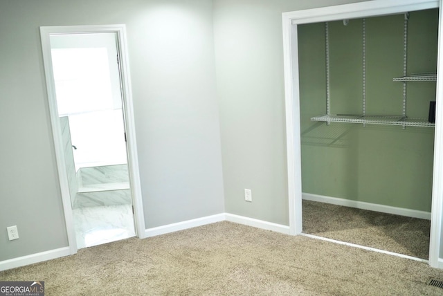 unfurnished bedroom with a closet, carpet floors, baseboards, and connected bathroom