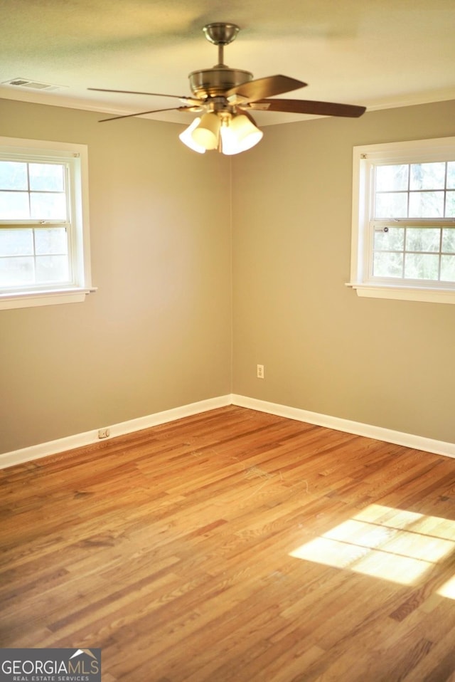 unfurnished room with a wealth of natural light, baseboards, and wood finished floors