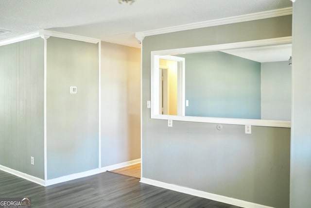 empty room featuring crown molding, baseboards, and wood finished floors