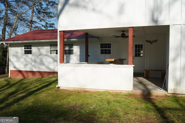 rear view of property with board and batten siding, ceiling fan, a lawn, metal roof, and crawl space