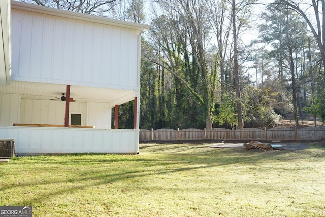 view of yard featuring a ceiling fan, cooling unit, and fence