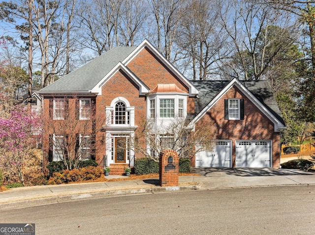 view of front of house featuring brick siding, driveway, an attached garage, and a shingled roof