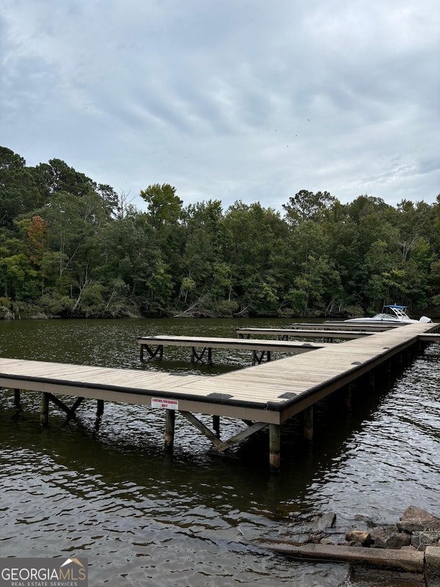 view of dock with a water view and a wooded view