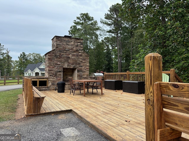 wooden terrace with an outdoor stone fireplace, outdoor dining space, and a grill