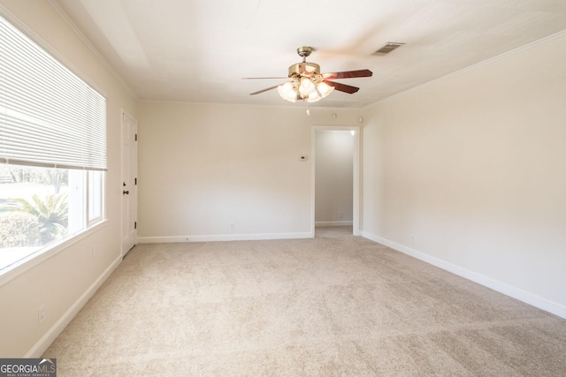 spare room with ceiling fan, baseboards, light colored carpet, and ornamental molding