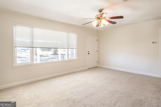 empty room featuring ornamental molding, baseboards, and light carpet