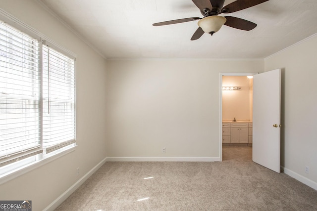 unfurnished bedroom featuring baseboards, ensuite bath, ceiling fan, crown molding, and light colored carpet