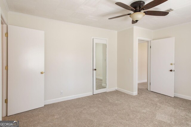 unfurnished bedroom with a ceiling fan, visible vents, baseboards, carpet floors, and crown molding