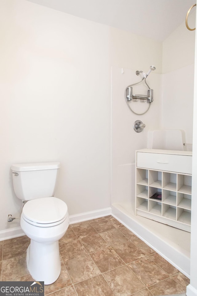 bathroom featuring toilet, baseboards, and walk in shower