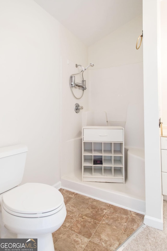 bathroom with baseboards, toilet, and walk in shower