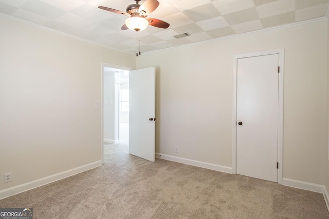 spare room featuring light colored carpet, baseboards, a ceiling fan, and ornamental molding