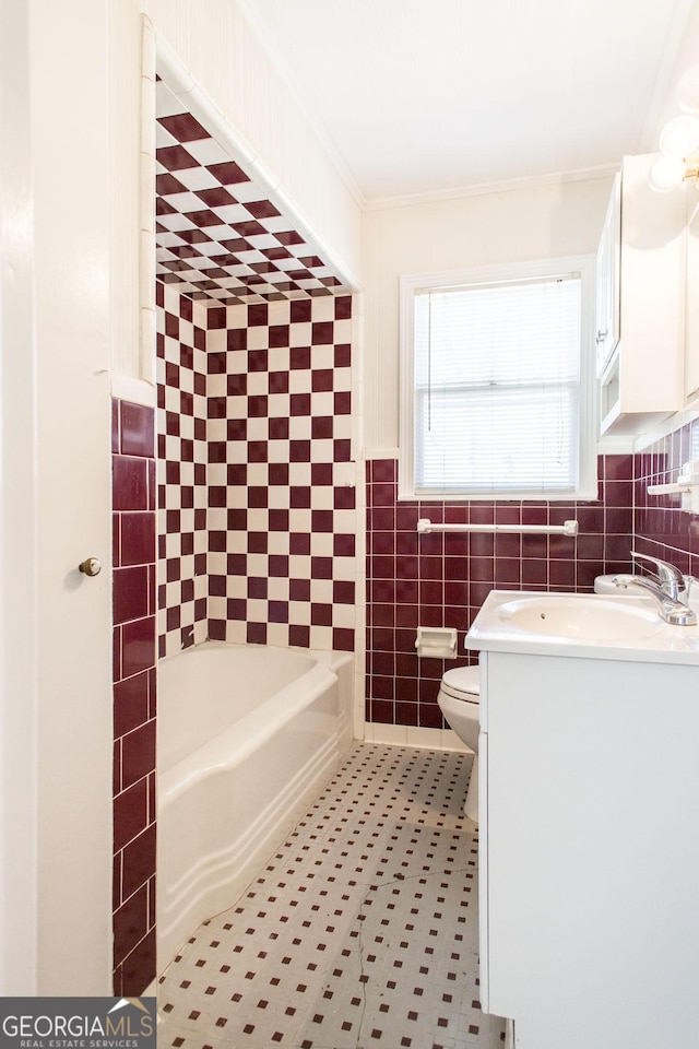 full bathroom with toilet, ornamental molding, a tub, tile walls, and vanity