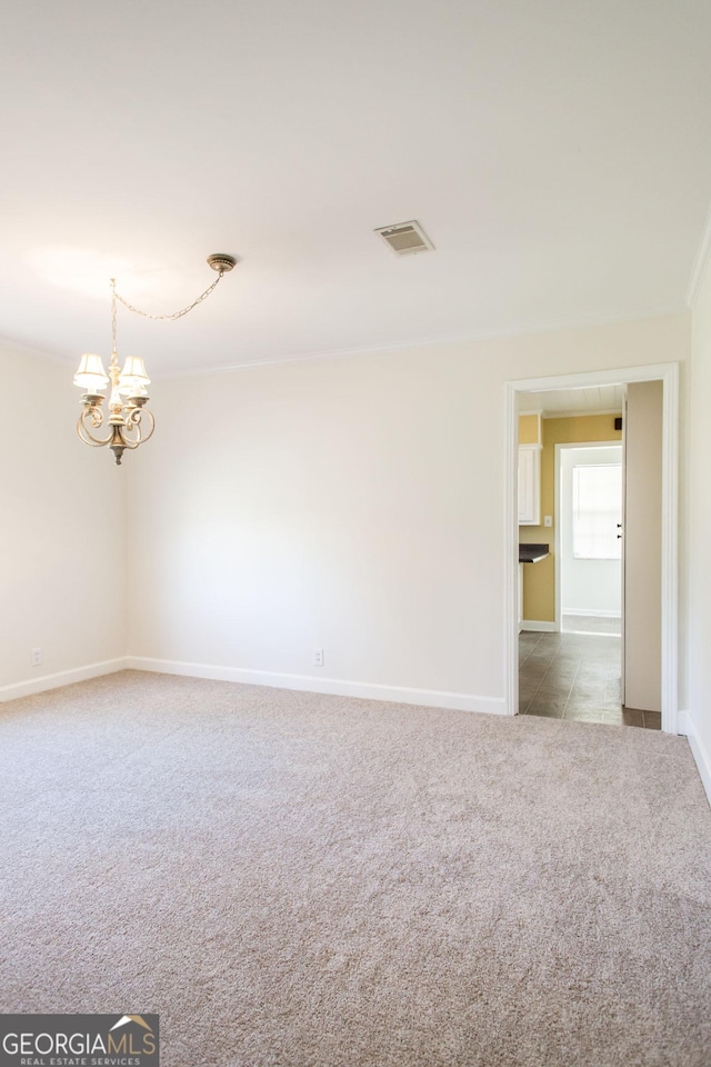 unfurnished room featuring visible vents, carpet floors, an inviting chandelier, crown molding, and baseboards