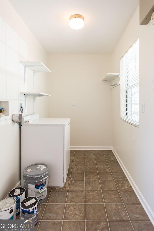 washroom with baseboards, washer / dryer, dark tile patterned floors, and laundry area