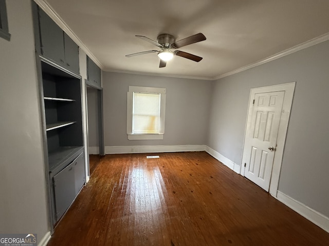 unfurnished bedroom with dark wood-style flooring, a ceiling fan, baseboards, and ornamental molding