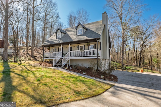 view of front facade with driveway, a front lawn, a porch, stairway, and a chimney