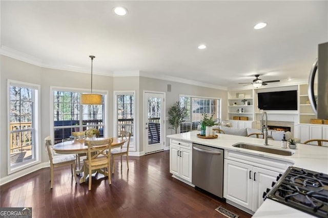 kitchen with a ceiling fan, dark wood finished floors, a sink, dishwasher, and crown molding