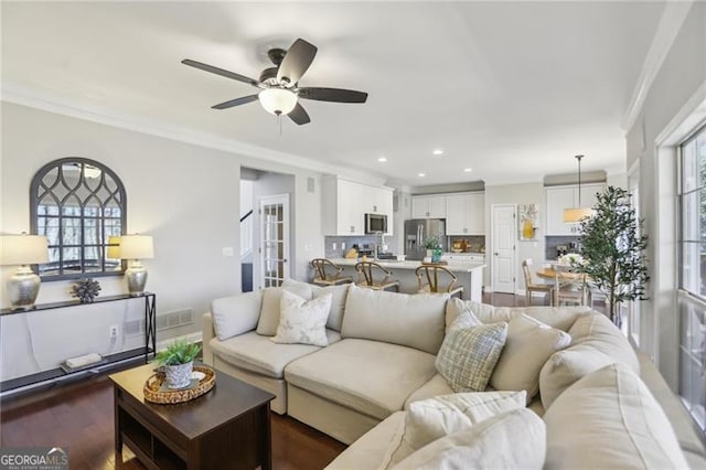 living room featuring dark wood finished floors, crown molding, recessed lighting, and ceiling fan