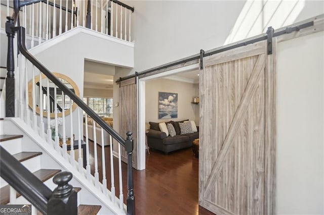 stairs featuring a barn door, a high ceiling, and wood finished floors