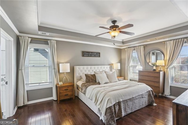 bedroom featuring visible vents, baseboards, a tray ceiling, ornamental molding, and wood-type flooring