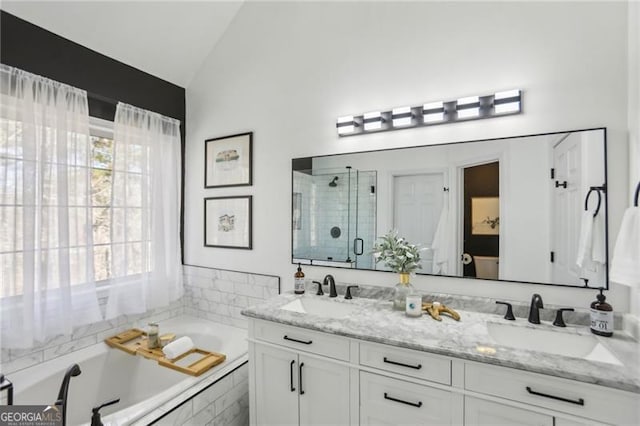 full bath featuring a shower stall, a garden tub, lofted ceiling, and a sink