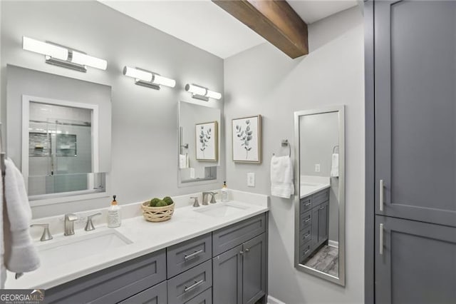 bathroom with a sink, beam ceiling, a shower with shower door, and double vanity