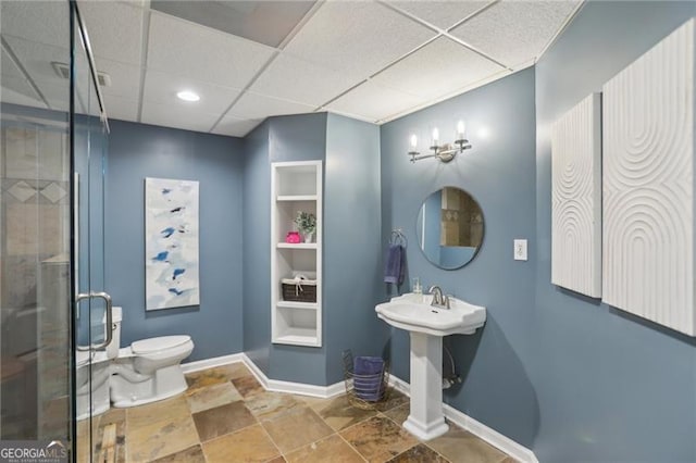 full bathroom with a paneled ceiling, baseboards, toilet, and a shower stall