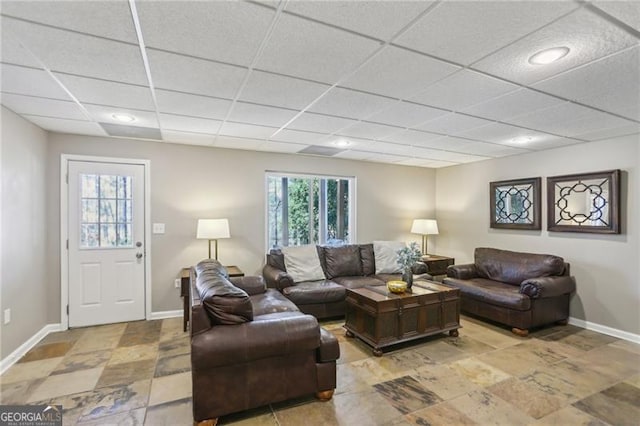 living room featuring a paneled ceiling and baseboards